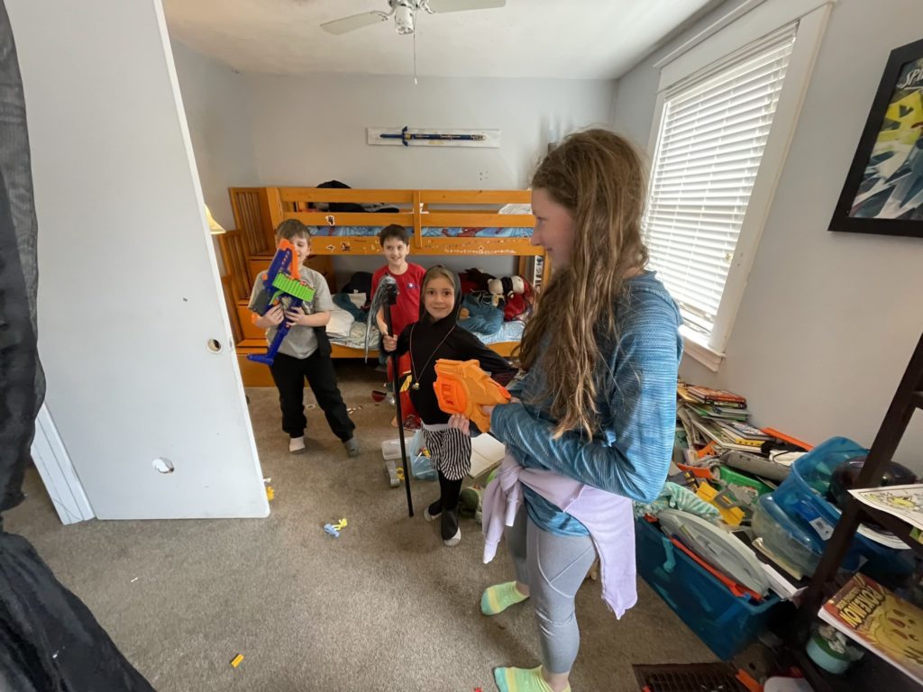 A photo of Vinny, Theo, Ainsley, and Rayleigh in Vinny and Theo's room. Vinny and Rayleigh are holding Nerf guns and Ainsley is dressed like the Grim Reaper