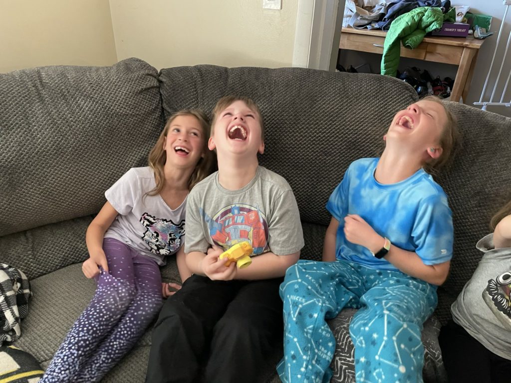 A photo of Ainsley, Vinny, and Dillon laughing hysterically on the couch