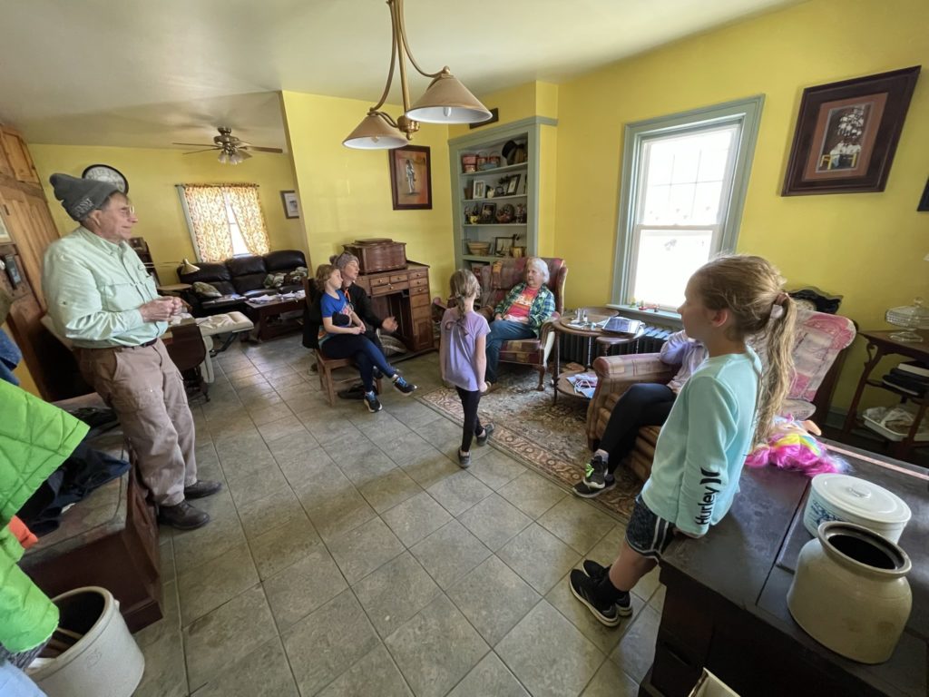 A photo of Uncle Calvin, Grayson, Kelsey, Ainsley, Aunt Marcia, Rayleigh, and Dillon in Calvin and Marcia's living room.