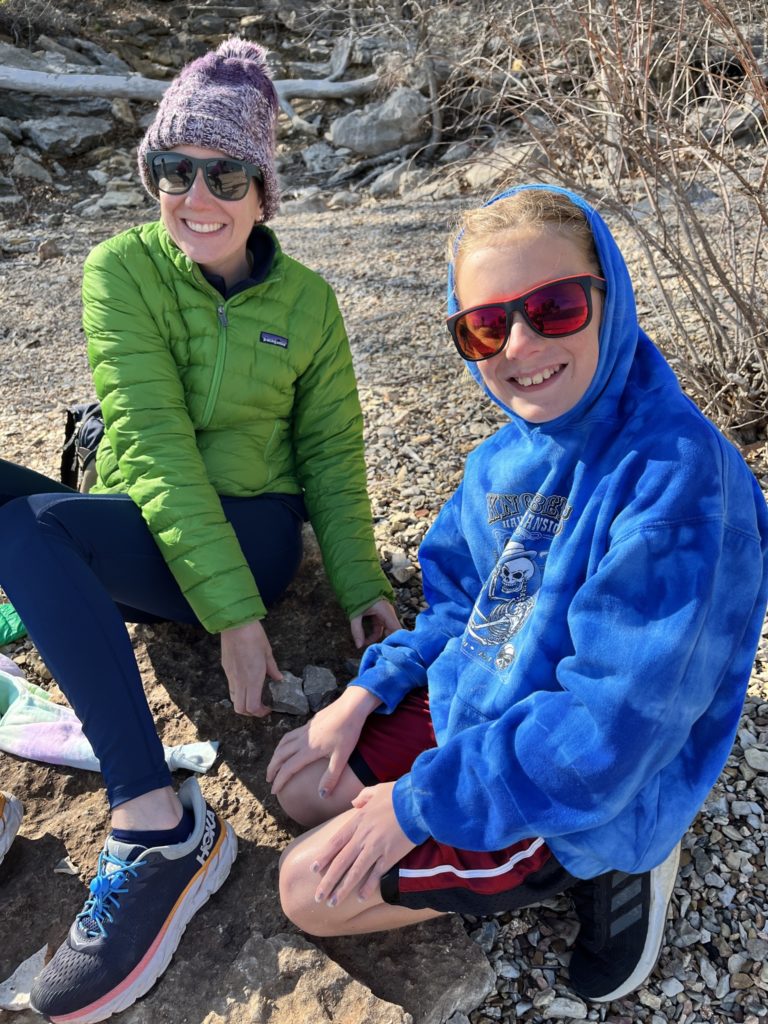 A photo of Kelsey and Dillon both wearing sunglasses smiling at the camera while looking for fossils