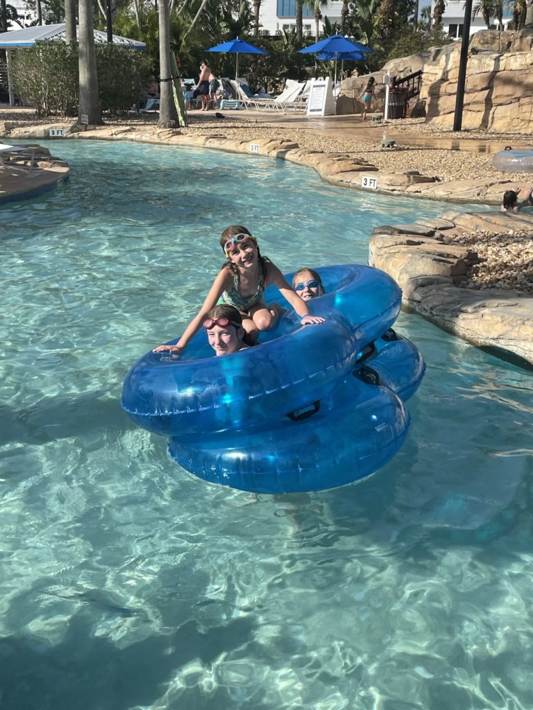 A photo of Rayleigh, Ainsley, and Dillon in two double inner tubes stacked on top of each other floating down the lazy river