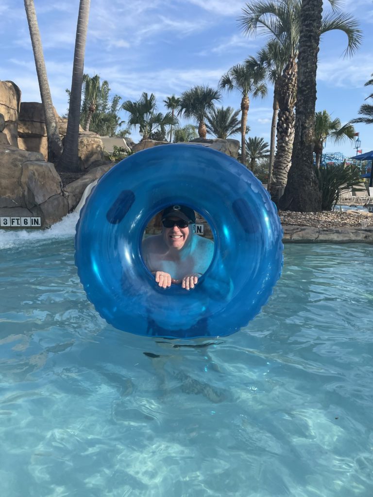 A photo of Kevin poking his head out of an inner tube up on end in the water