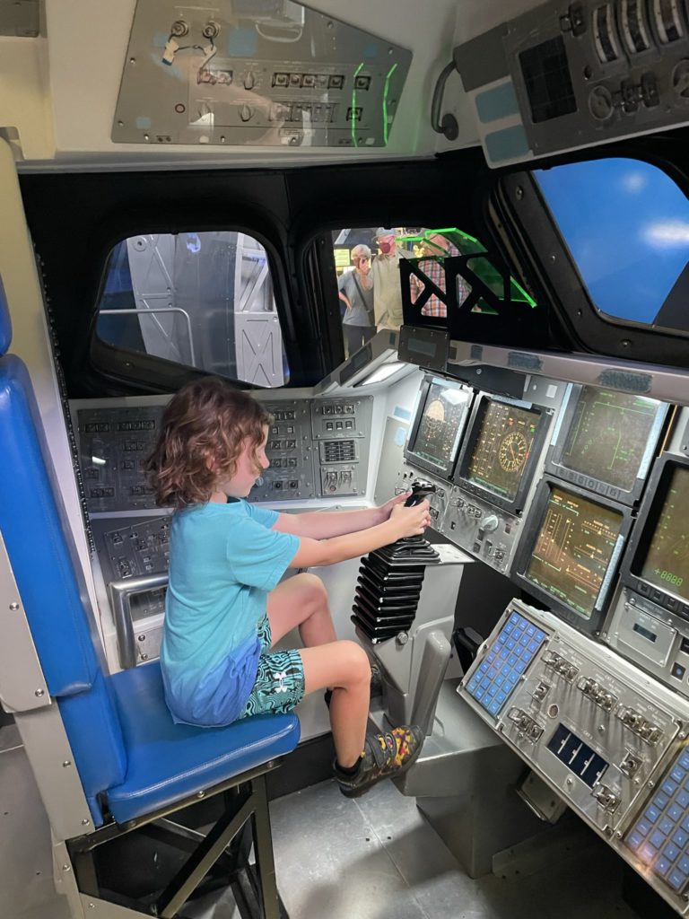 A photo of Grayson operating the joystick on a replica of the space shuttle cockpit