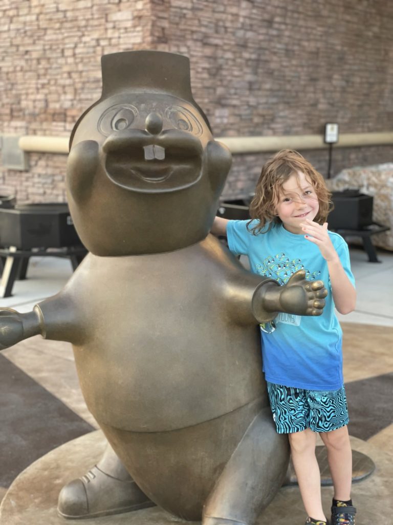 A photo of Grayson standing next to a statue of Buc-ee the Beaver