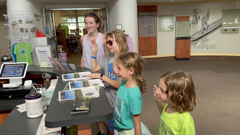 A photo of Rayleigh, Dillon, Ainsley, and Grayson taking the Junior Ranger pledge in the visitor's center