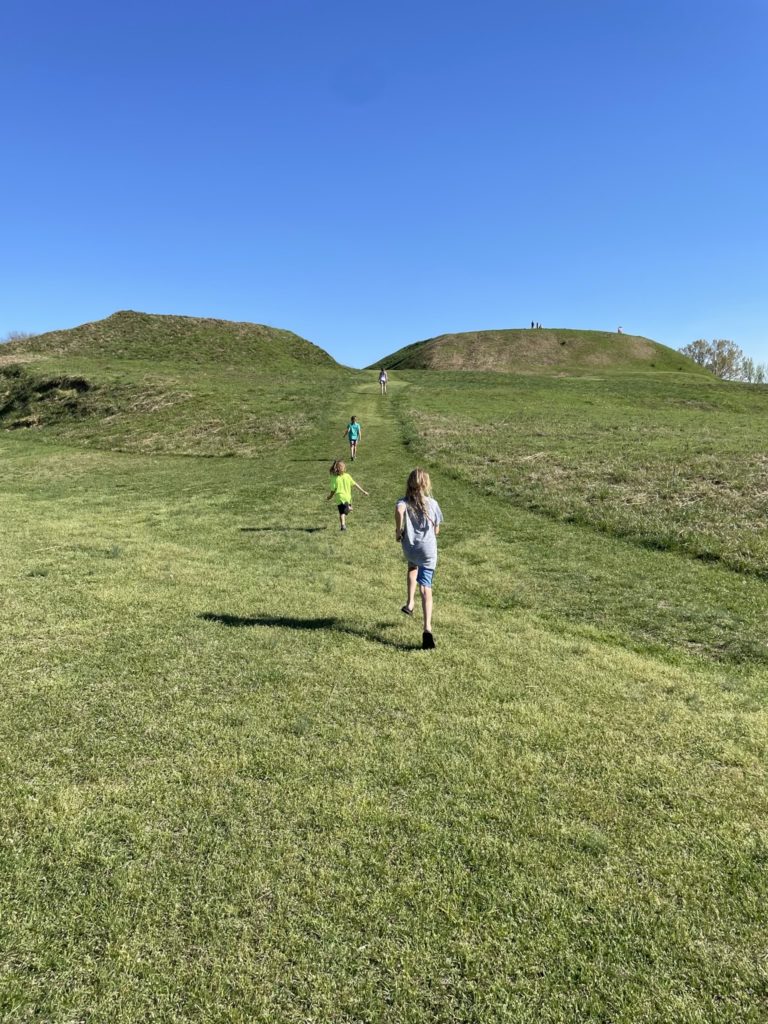 A photo of Dillon, Grayson, Ainsley, and Rayleigh running up the hillside to mounds that were built on the top