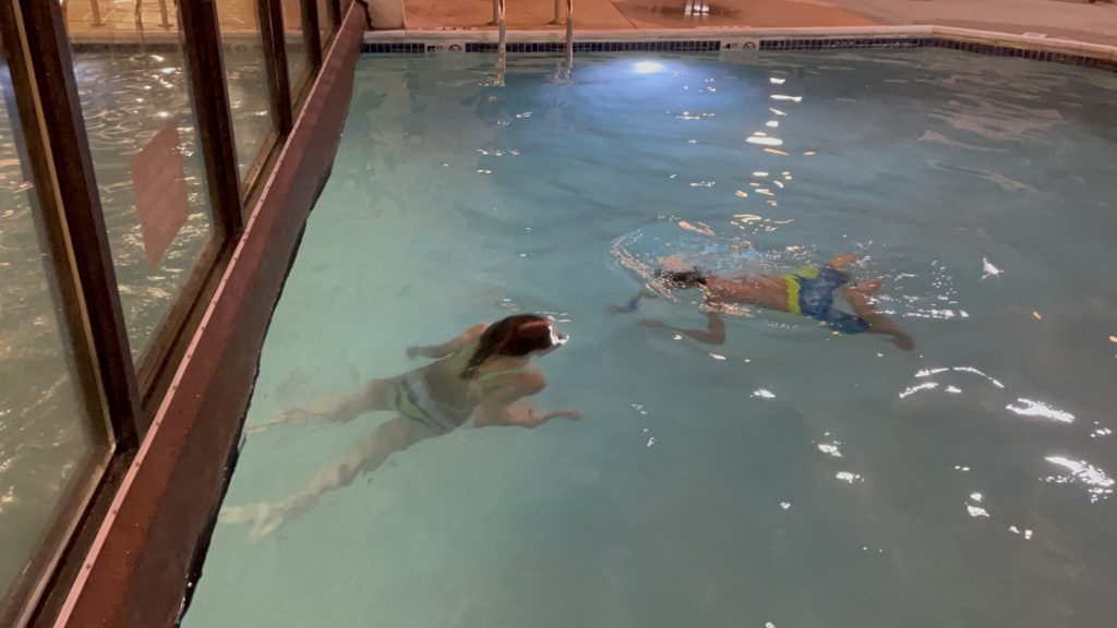A photo of Rayleigh and Dillon swimming in the outside part of an inside/outside hotel pool