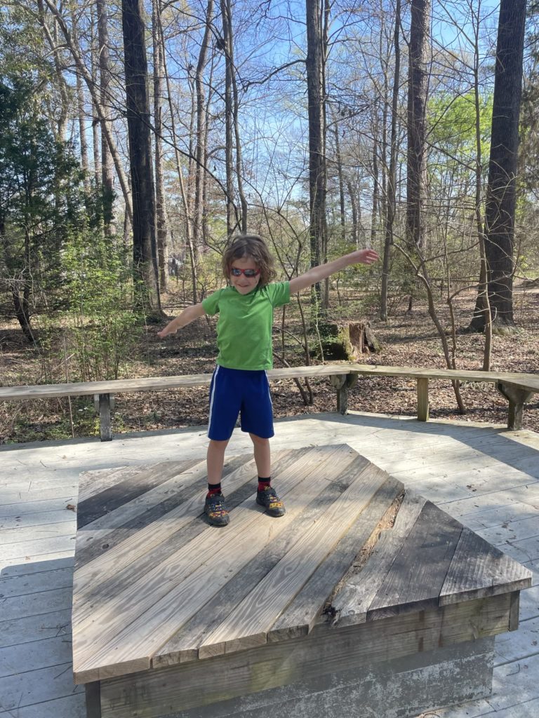A photo of Grayson striking a pose on an elevated platform in the woods