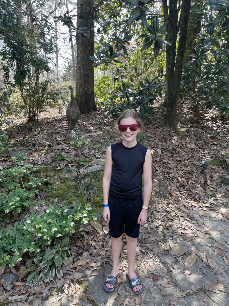 A photo of Dillon with a sculpture of a turkey in the woods behind him