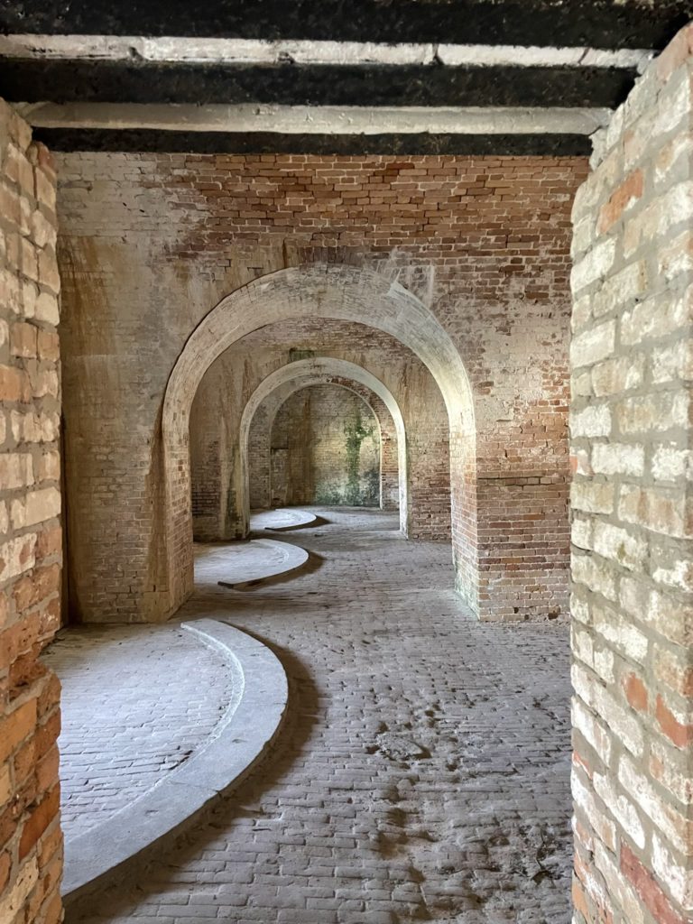 A photo of consecutive brick archways inside the fort with tracks for where cannons would have been mounted and swiveled to aim