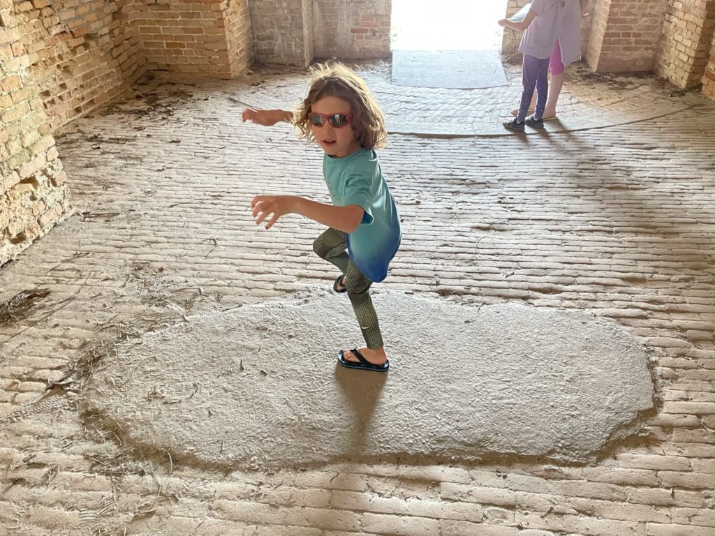 A photo of Grayson stepping on a repaired section of the brick floor of the fort that looks like a giant footprint made of concrete