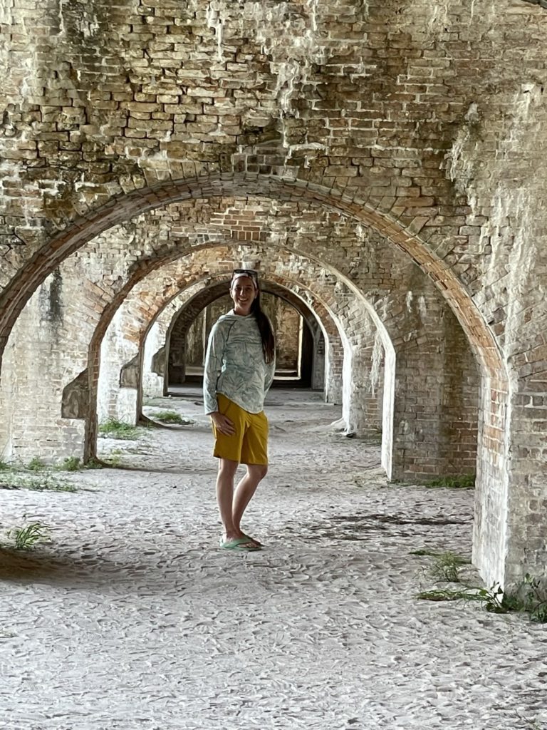 A photo of Kelsey standing under a brick arch in the fort
