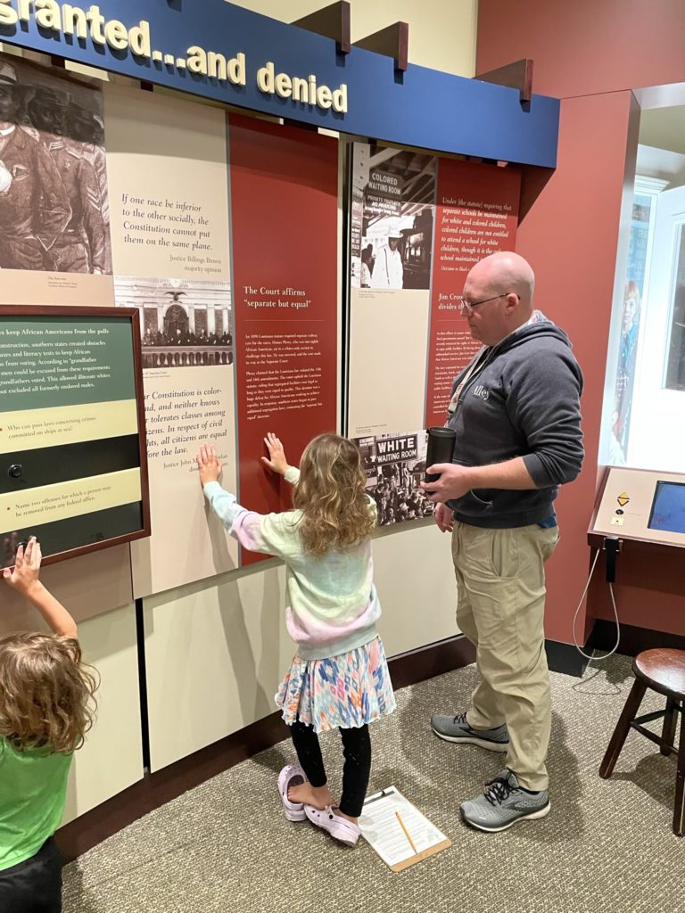 A photo of Ainsley reading an exhibit about the history of "separate but equal" while Kevin looks on
