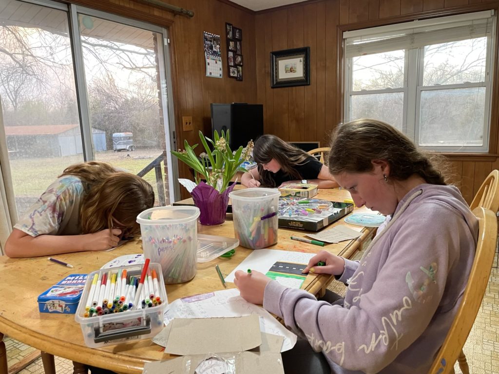 A photo of Kate, Molly, and Rayleigh coloring at the kitchen table