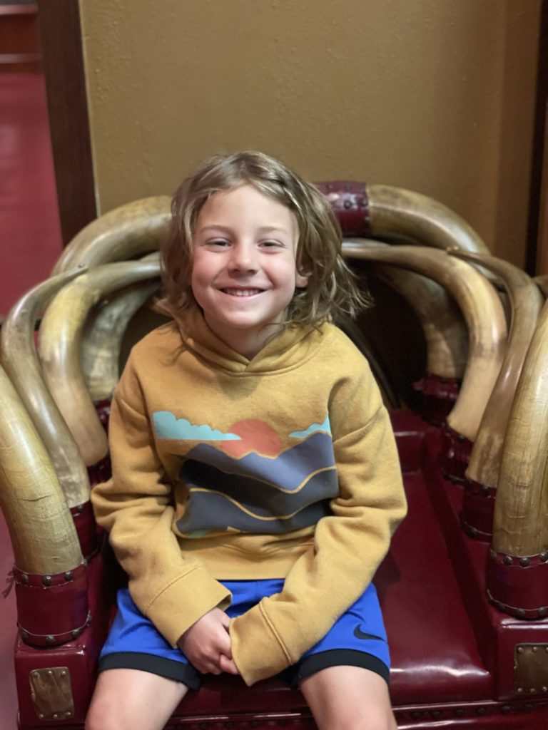 Grayson sitting on a chair that is partially made out of horns from longhorn cattle
