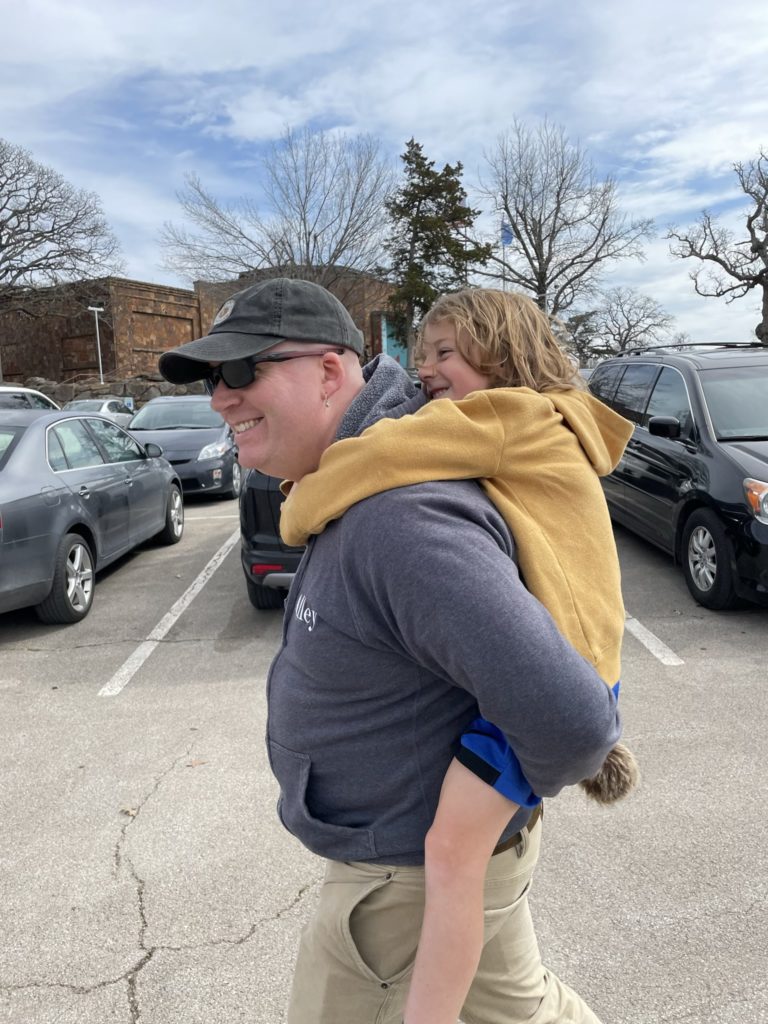 A photo of Kevin giving Grayson a piggyback ride through the parking lot