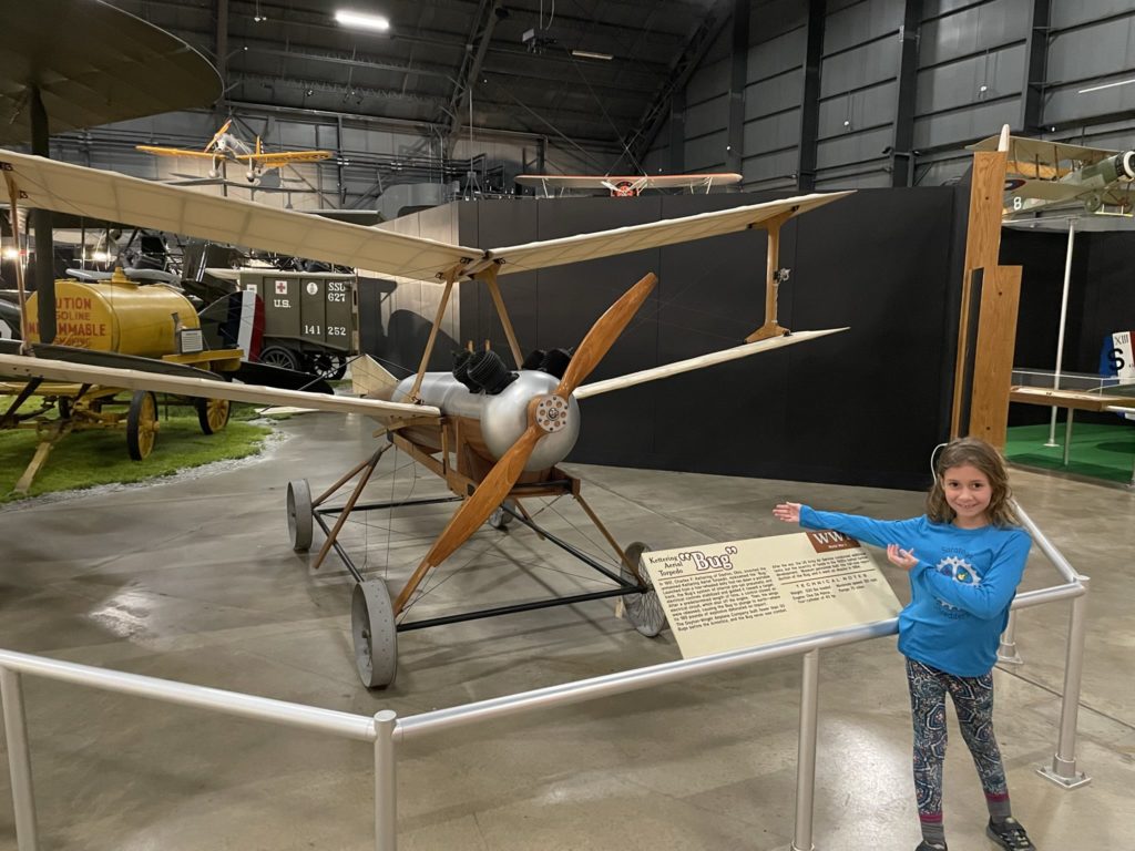 A photo of a small biplane called the Bug with Ainsley posing in front of it