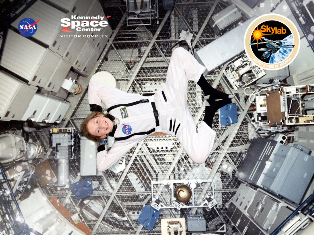 A photo of Dillon in an astronaut costume appearing to float weightless in a space station