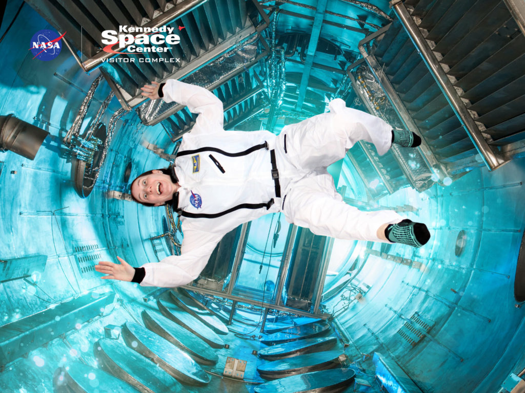 A photo of Kelsey in an astronaut costume appearing to float weightless in a space station