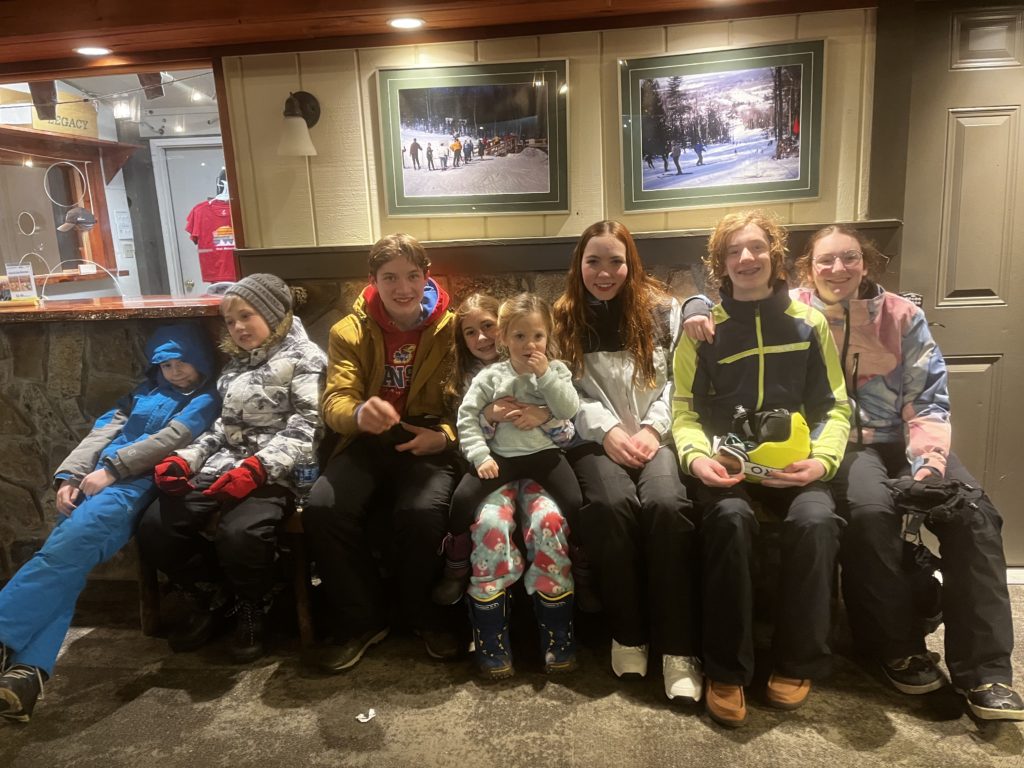 Eight kids on skis and snowboards.